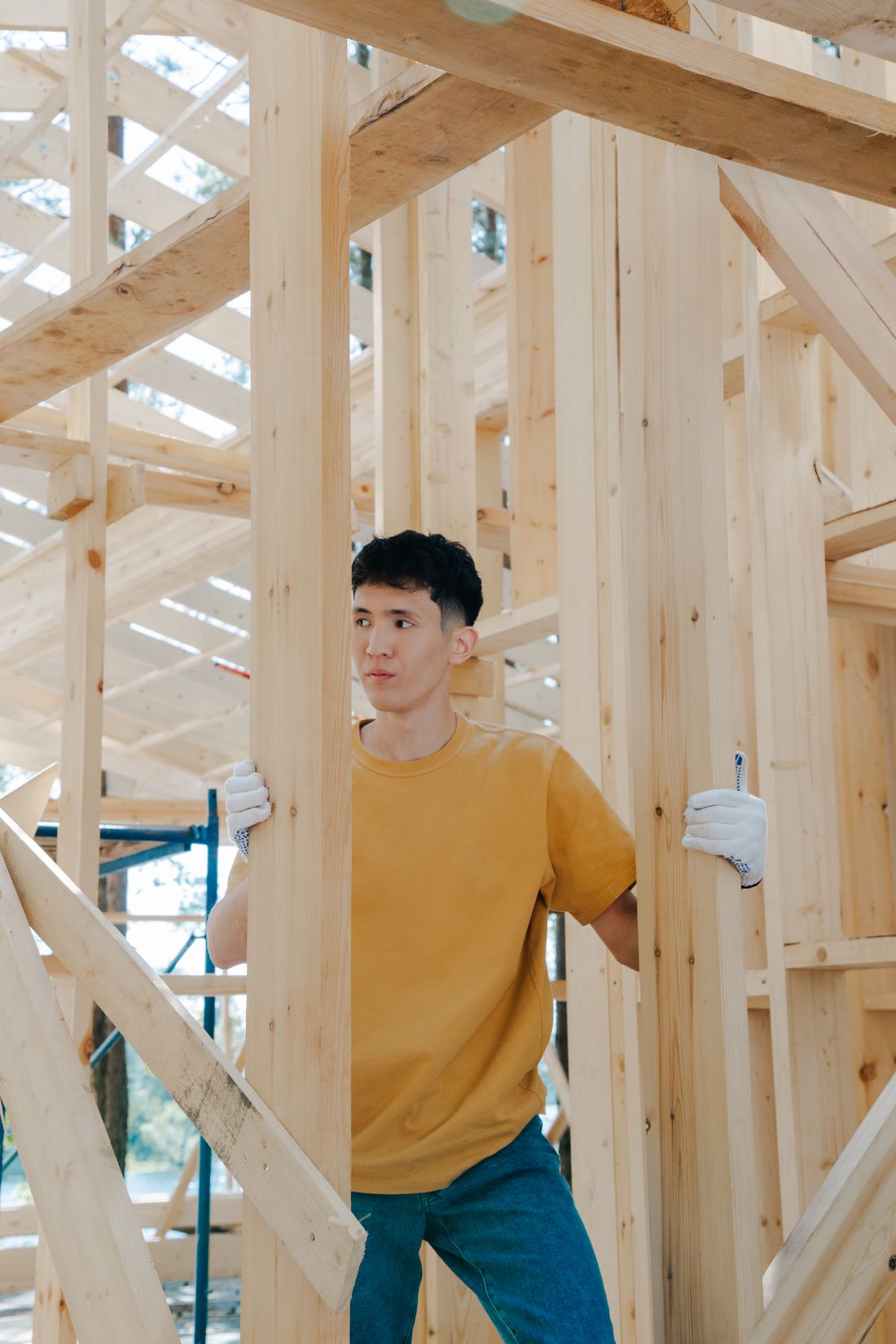 A young male worker inspects wooden beams at a construction site