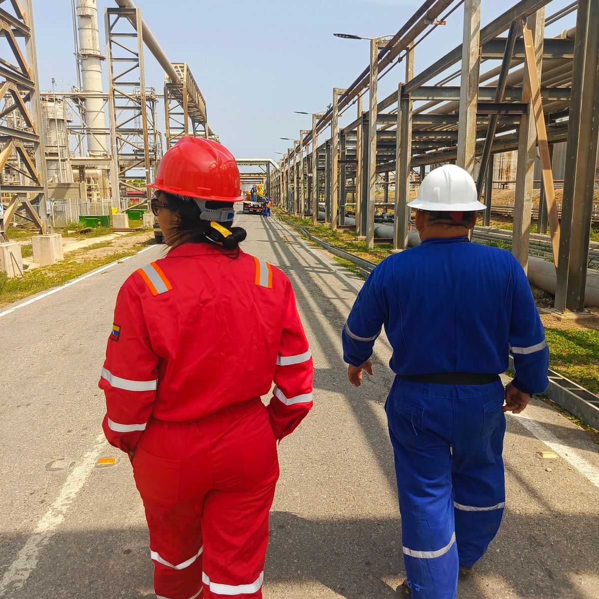 Two workers in protective gear walk through an industrial plant, ensuring safety compliance
