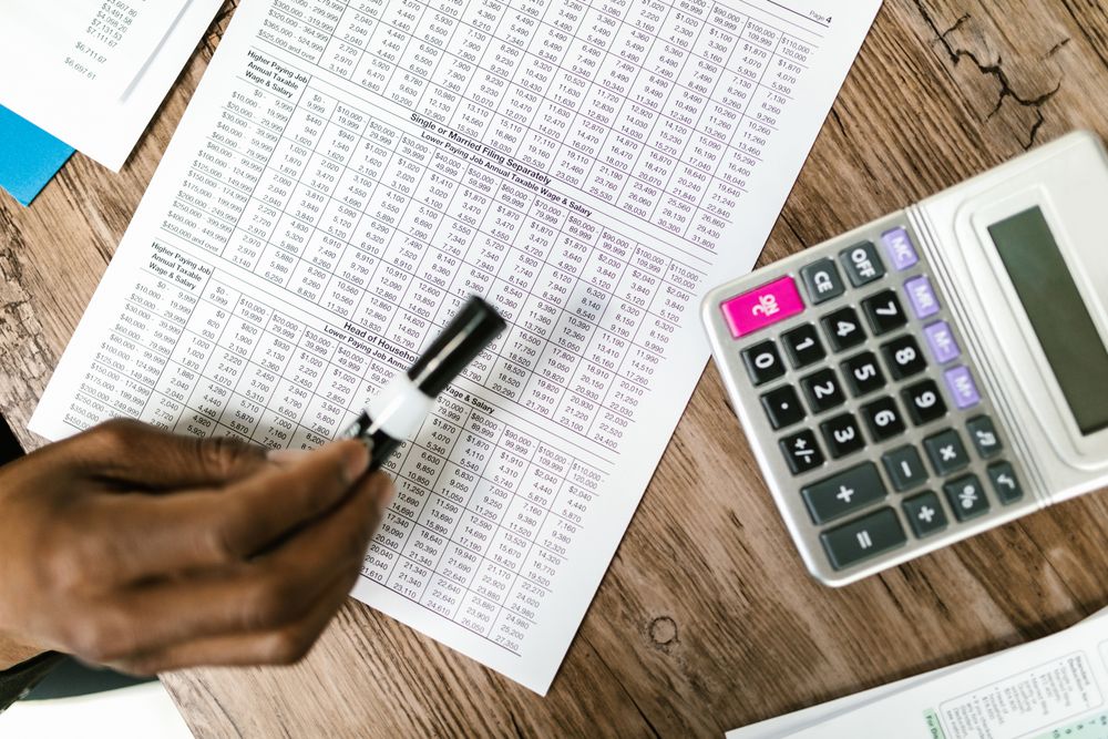 Close-up of tax documents and calculator on wooden table, highlighting financial analysis