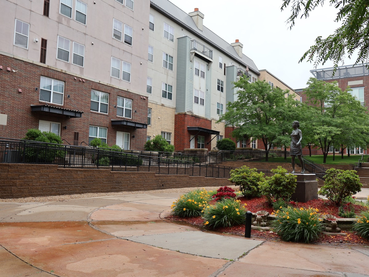 Multi-story building with statue, trees, and garden