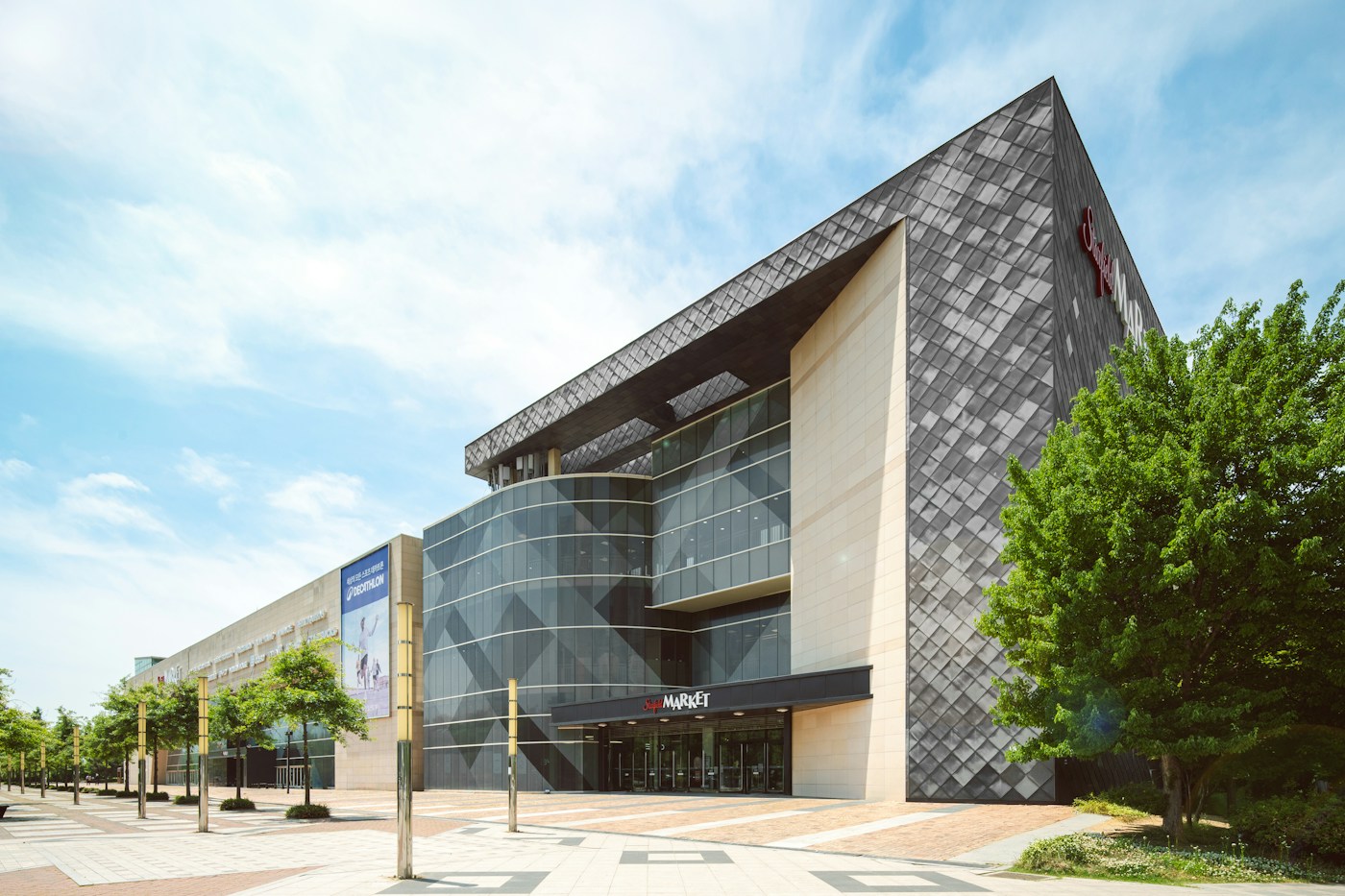 Modern shopping mall building with glass facade and tiled exterior under a blue sky